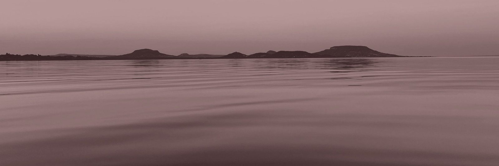 The ten volcanic hills of the Balaton Uplands seen across the lake from Balatongyörök at dusk